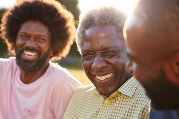 Senior black man laughing with his two adult sons, close up