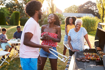 Couple laughing at a multi generation family barbecue - Powered by Adobe