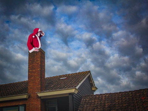 Merry Christmas and happy holidays! Santa Claus sitting in a chimney and looking at distance.