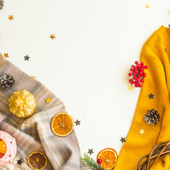 Winter sweater, scarves and decorations on a white background with oranges, stars and candles. Top view, flat lay, copy space