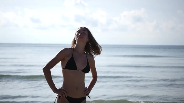 Beautiful slender girl in a bathing suit standing on the beach, spinning. enjoying the sun. HD, 1920x1080, slow motion
