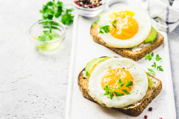 Avocado, cream cheese and fried egg sandwich. Selective focus, space for text.