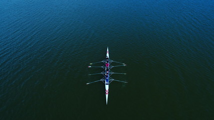 Boat coxed four rowers rowing on the tranquil lake. Aerial view of rowing and rowers.