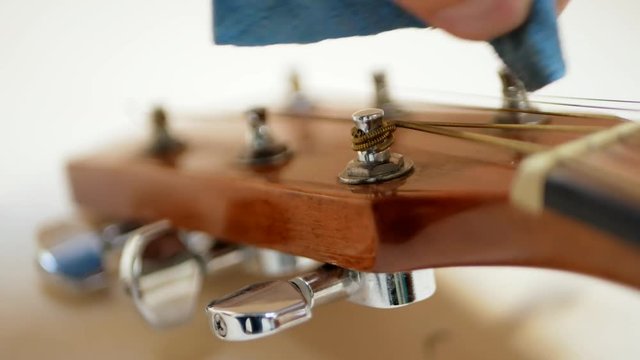 Acoustic guitar player cleans a dusting musical instrument
