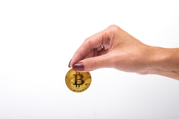 A female hand holds bitcoin on an isolated background. Close up female holds in hand bitcoin, metal coin of golden color isolated on white background.  Copy space.