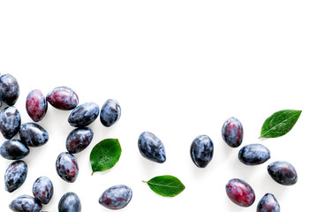 Blue plum for dessert. Purple plum and leaves pattern on white background top view copy space