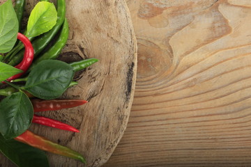 heap of chili pepper with leaves of lemon on wooden background