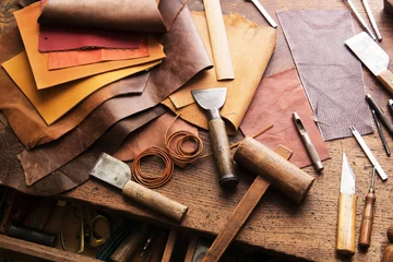 Fotobehang Leather craft or leather working. Selected pieces of beautifully colored or tanned leather on leather craftman's work desk . © killykoon