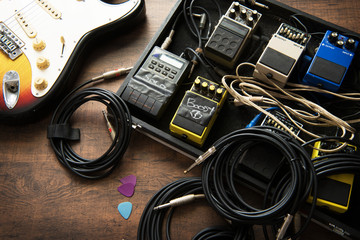 Electric guitar and guitar audio processing effects on a studio floor. Electric guitar and stomp box type effectors and cables on studio floor. Intentionally shot with low key tone.