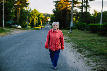 Elderly woman walking down the street in village.