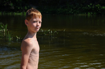 The boy is bathing on the river.