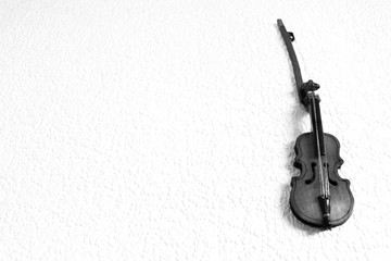Black and white photo Closeup of Small violin on a white wall