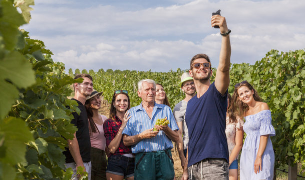 group of tourists take a selfie outdoor in the vineyard during a lesson about growing wine