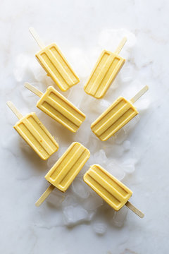 Overhead view of mango popsicles on ice cubes