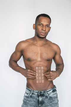 Crop black shirtless man with bar of chocolate