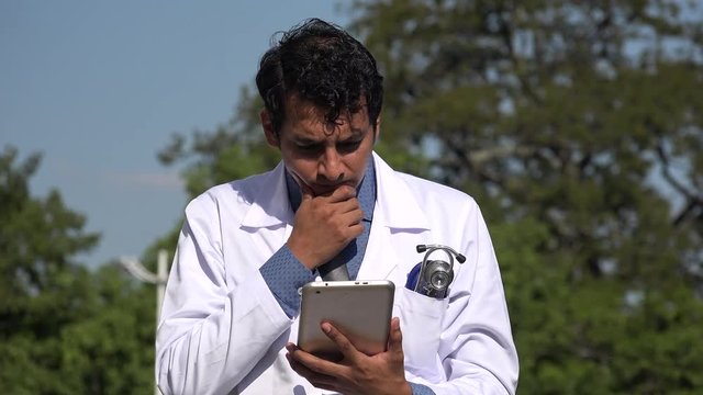 Worried Hispanic Doctor Using Tablet