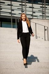 Young business woman walk on stairs leaving office building