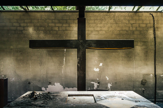 Altar and huge cross in a church or chapel destroyed by fire of a candle. Remains of a burned religious place where you can see the power of fire.