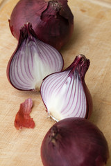 Rohe Zwiebeln und Zwiebelh&auml;lften auf dem Schneidebrett