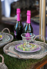Osterdekoration mit Kerze in Eierform im Glas und Champagnerflaschen im Hintergrund