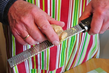 Person reibt Ingwer mit Raspel 