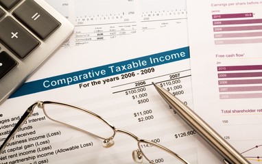 Obraz premium Calculator, Glasses And Pen On Comparative Taxable Income Report