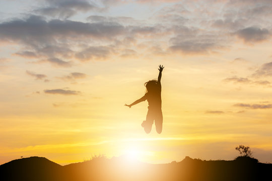 Silhouette of a Happy young woman jumping at the sunset, Freedom and enjoyment concept.