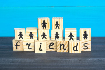 Naklejka premium Wooden cubes with word Friends and drawn people on the blue background.