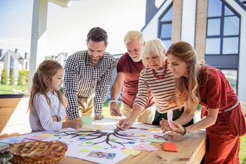 Team work. Amazing child standing in semi position while looking at notes