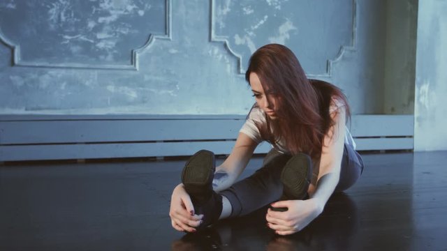 Pretty girl is straching out her legs on the floor.