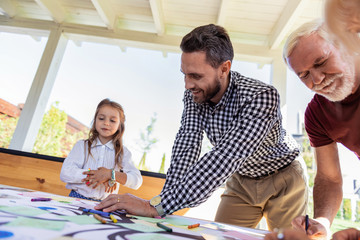 Love my family. Pleased brunette male keeping smile on his face while looking at picture of his kid