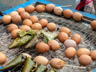 Grilled egg and sticky rice in banana leaf, an easy meal in Thai traditional style. One of Thai delicious street food recipe cooking by grilled on charcoal.