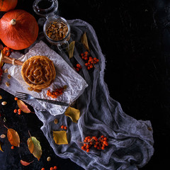 Autumn concept. Pumpkin pancakes with caramel topping, with pumpkins, leaves on a dark background.