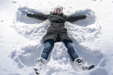 Fototapeta na wymiar happy young woman lying on snow fur in wintertime. Young happy woman kidding on snow in winter day