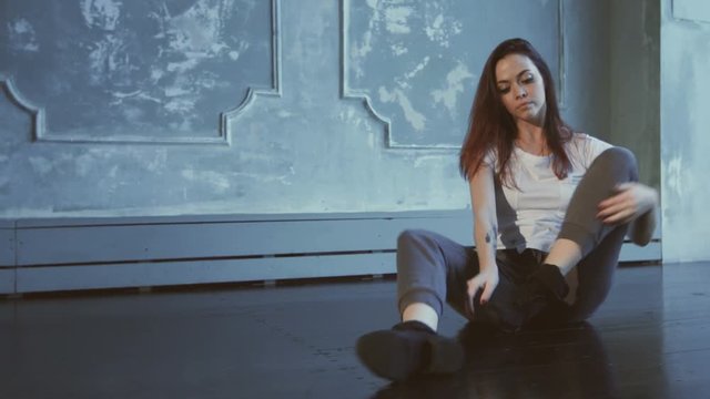 Girl is streching out her right leg in the hall.