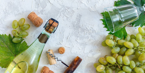 Bottle of white wine, grapes, glass and corkscrew.