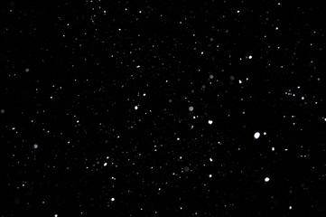 Snowstorm texture. Bokeh lights on black background, shot of flying snowflakes in the air