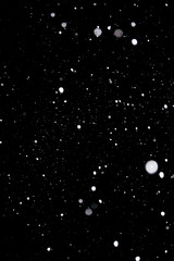 Snowstorm texture. Bokeh lights on black background, shot of flying snowflakes in the air