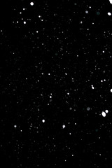 Snowstorm texture. Bokeh lights on black background, shot of flying snowflakes in the air