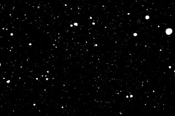 Snowstorm texture. Bokeh lights on black background, shot of flying snowflakes in the air