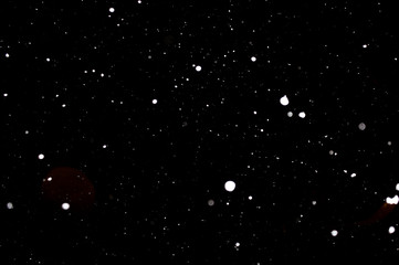 Snowstorm texture. Bokeh lights on black background, shot of flying snowflakes in the air
