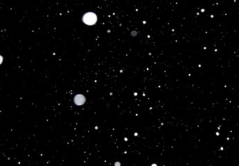 Snowstorm texture. Bokeh lights on black background, shot of flying snowflakes in the air