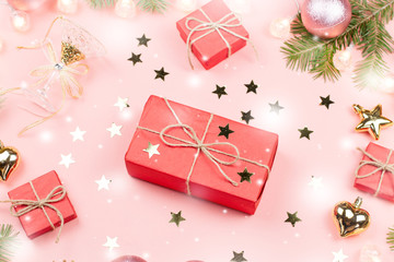 Christmas background with fir branches, lights, red giftboxes, pink decorations with snow falling