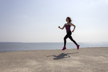 Young fit girl running and training on the beach