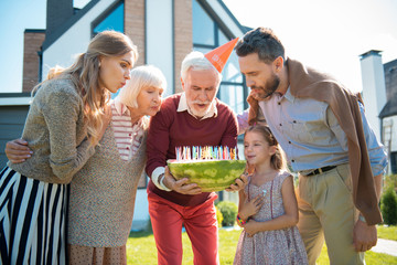 Birthday cake. Concentrated mature man bowing head while making wish