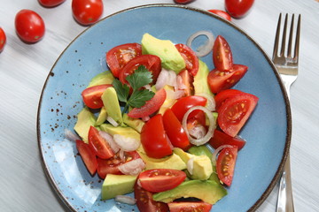 Fresh, healthy salad with tomatoes, avocado and onion.