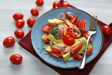 Fresh, healthy salad with tomatoes, avocado and onion.