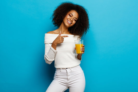 Beautiful smiling african american girl showing a glass of orange juice