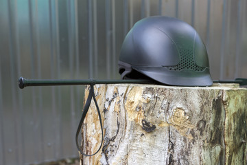 Equipment for horse riding: helmet and whip on the wood