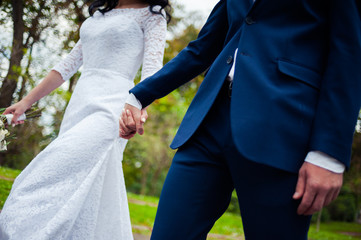 Beautiful bride with wedding bouquet  and groom walking in the park 